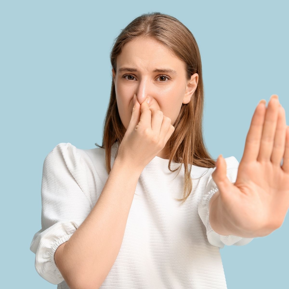Woman blocking unpleasant odours indoors, illustrating topical probiotic benefits for odour control and fresher home environments