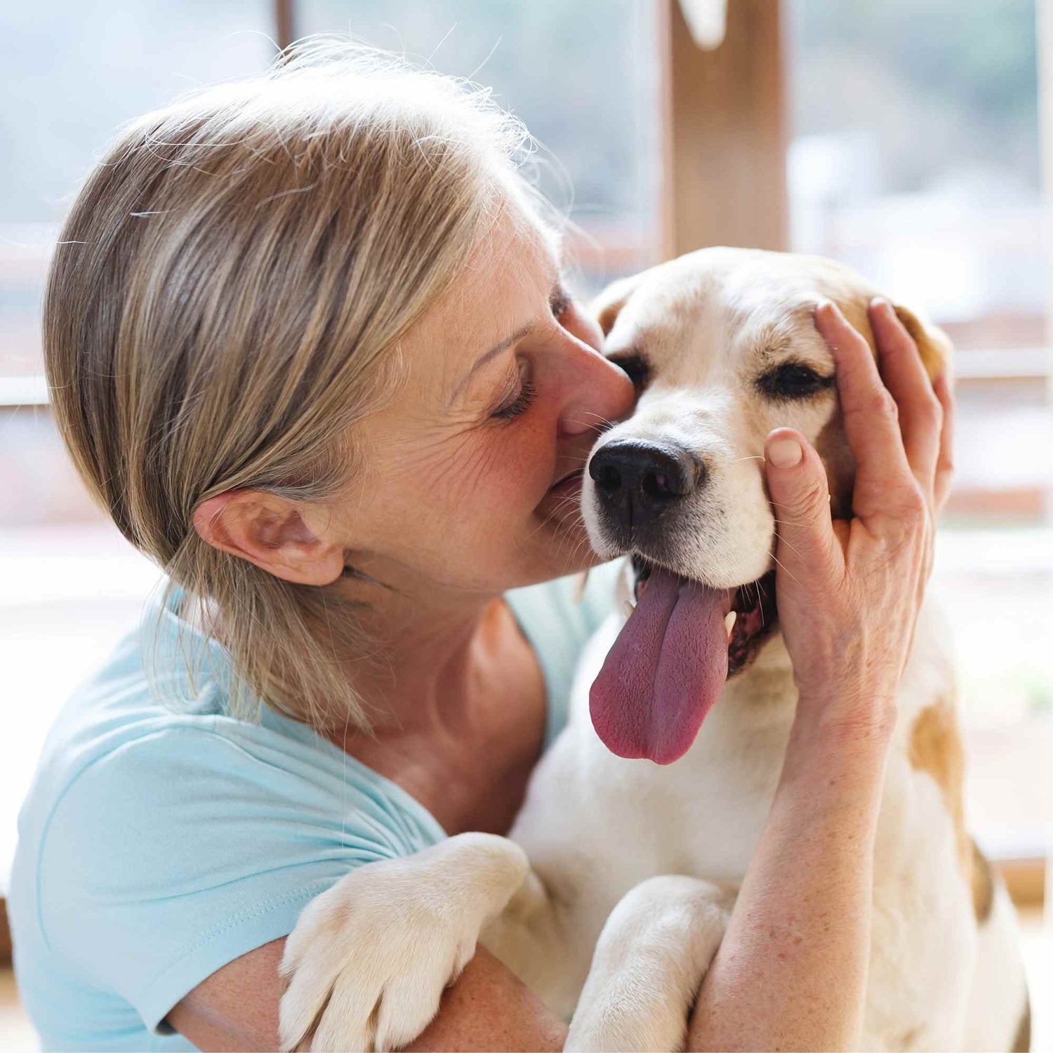 Owner kissing happy dog with fresh breath and healthy teeth after dental care